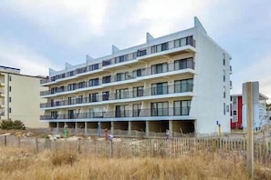 Um edifício com várias andares, varandas, um telhado plano e fachada simples.