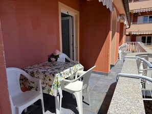 Ein Balkon mit einem Tisch für zwei Personen, weißen Stühlen und einer Tür.