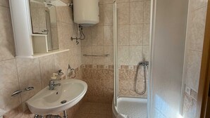 Un baño con lavamanos, espejo, inodoro y ducha.