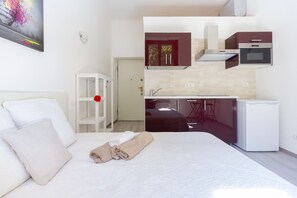 Ein kleines Hotelzimmer mit einem Bett, einer kleinen Küchenzeile und einer Tür zum Badezimmer.
