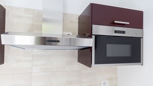 Una cucina con una cappa in acciaio inossidabile, un forno a incasso e un microonde.