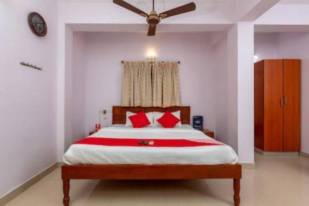 A bedroom with a wooden bed, a ceiling fan, a clock, and a wardrobe.