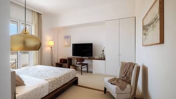 A modern hotel room with a bed, a desk, a television, and a chair.