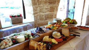 Un bufé con diversos quesos, frutas y verduras.