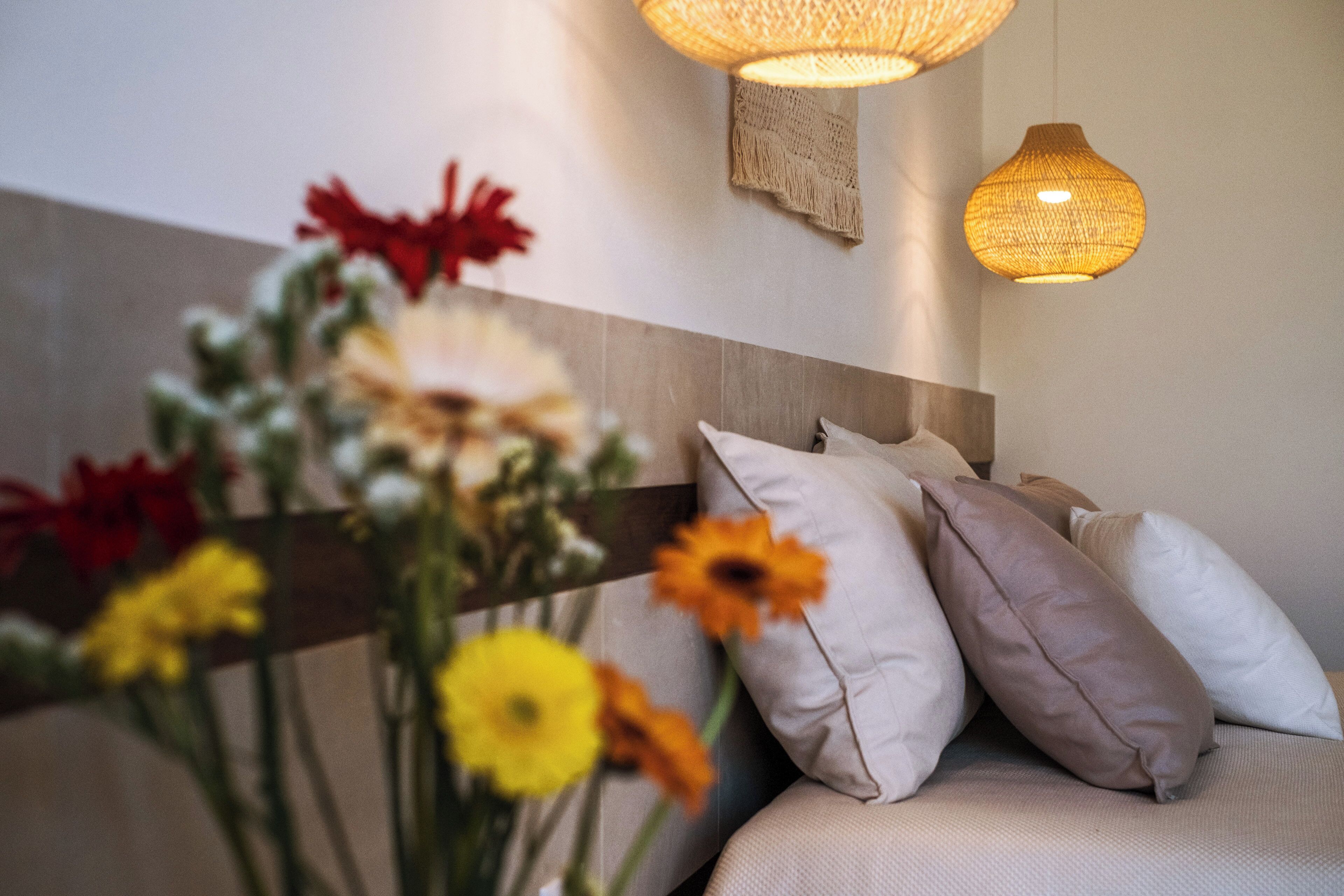Une pièce comprenant un lit, des oreillers et un luminaire fixé au mur.
