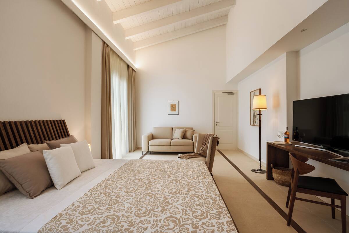 A hotel room with a bed, a sofa, a TV, and a desk.