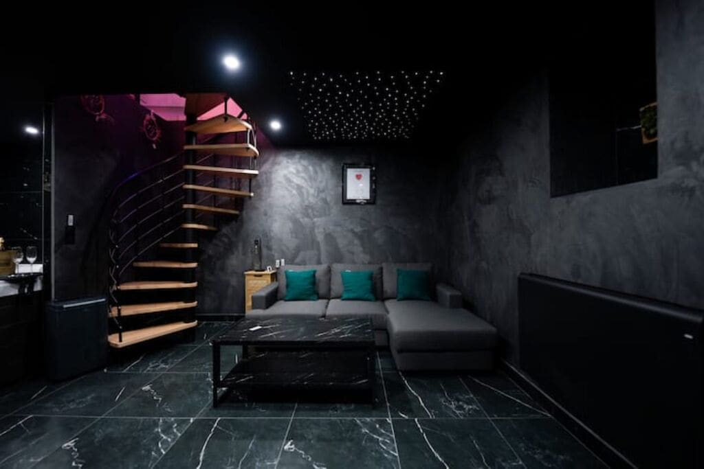 A modern interior with a staircase, a sofa set, and a marble floor.
