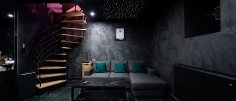 A modern interior with a staircase, a sofa set, and a marble floor.