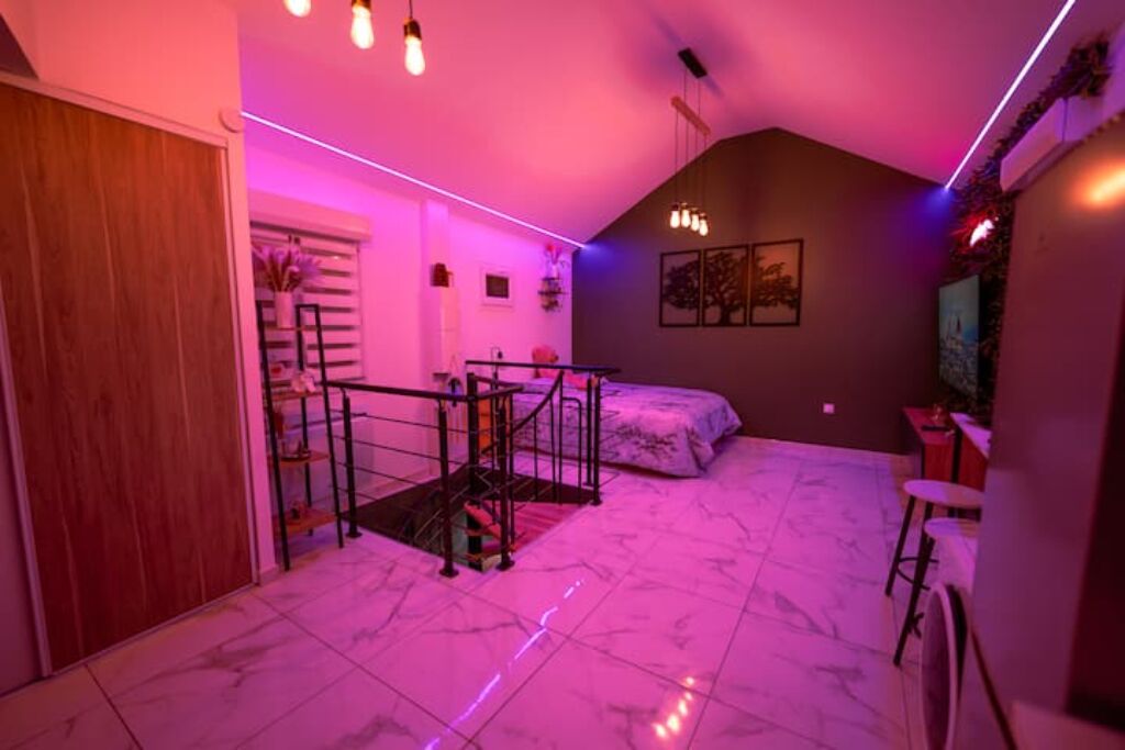 A bedroom with a bed, a staircase, and a small table.