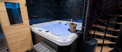 A modern spa room with a hot tub, wooden accents, and a marble wall.
