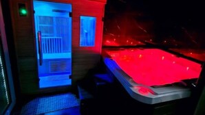 A spa room with a red heated tub and a blue-lit sauna. - Salle D'amour L'elixird'amour (Étampes-sur-Marne)