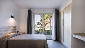 Habitación de hotel con dos camas, un amplio ventanal corredero al balcón y un diseño moderno.