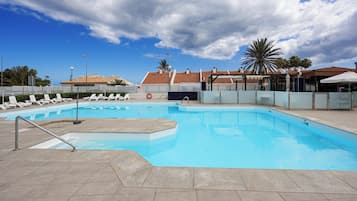 Una piscina con sillas de descanso, un flotador salvavidas y una palmera.
