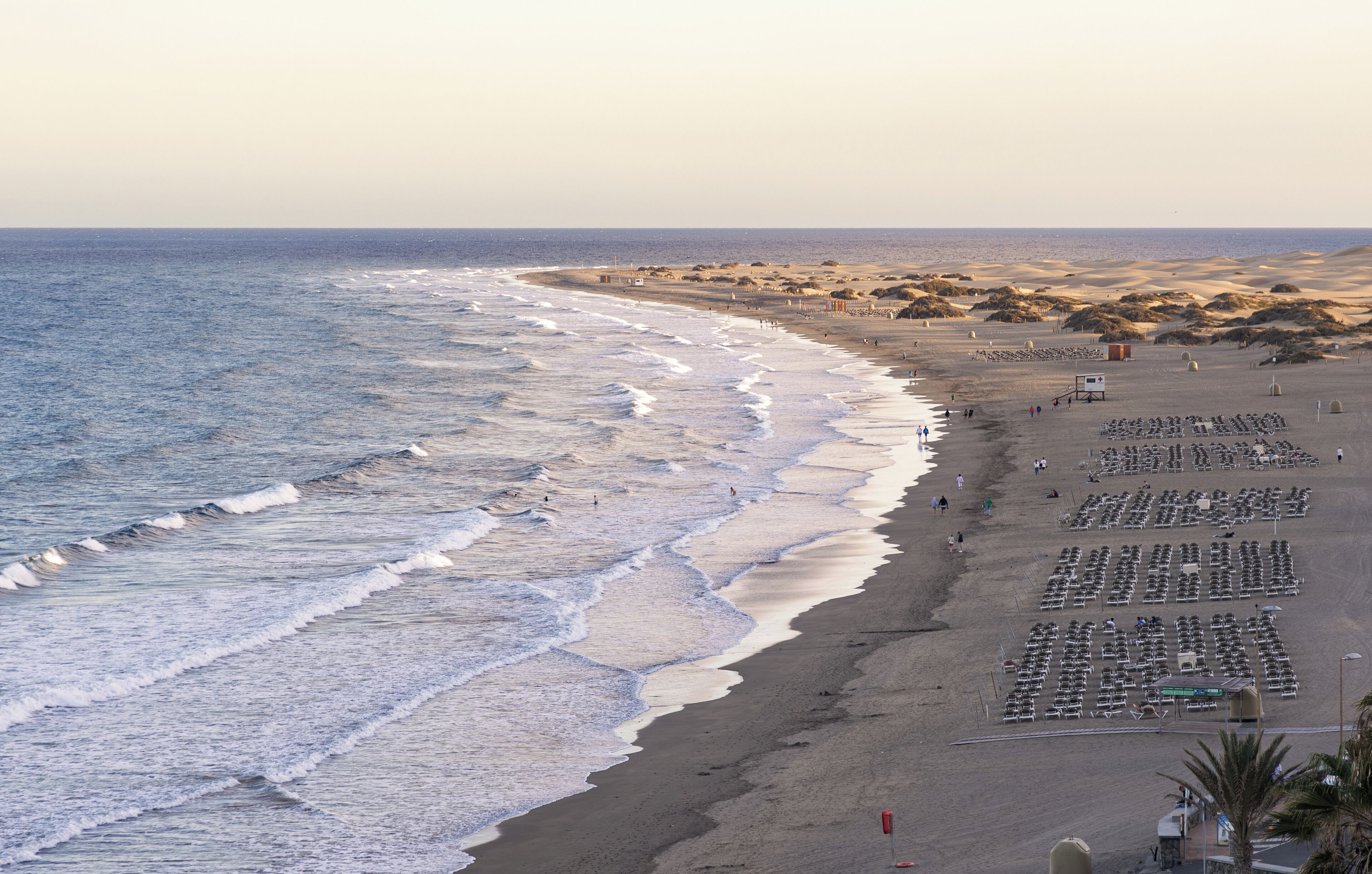 A beach with rows of sun loungers and a lifeguard tower.