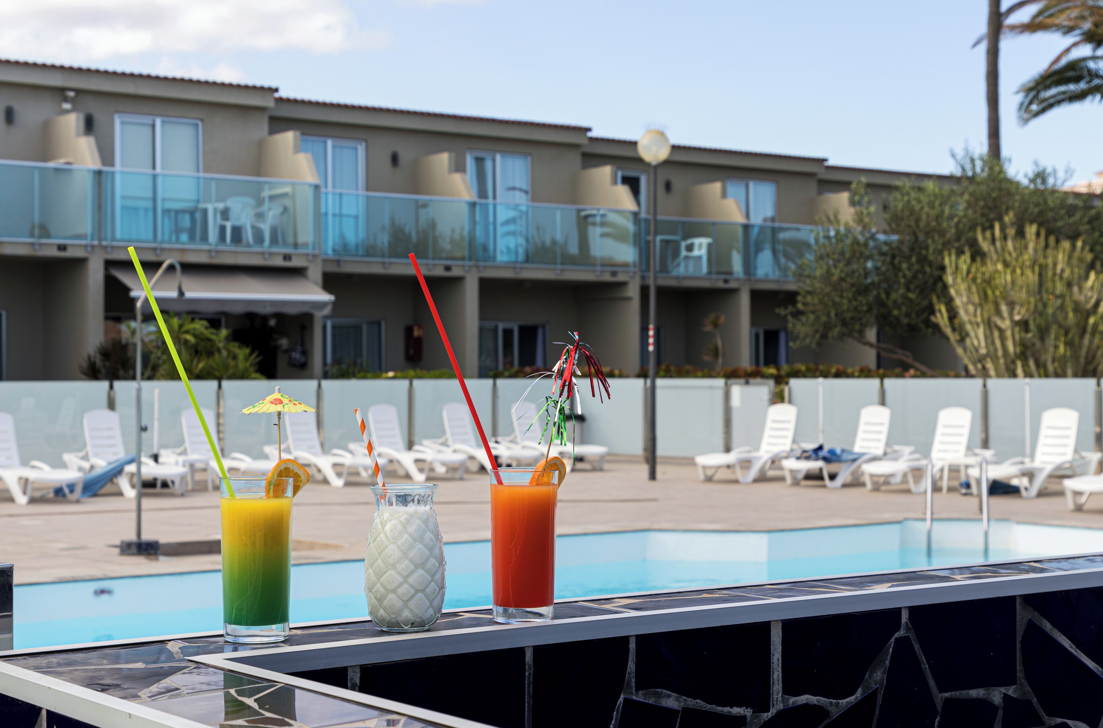A poolside area with lounge chairs and a building in the background.