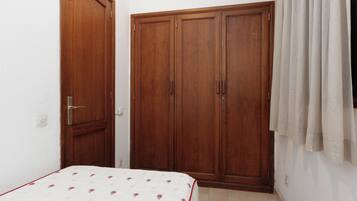 Un dormitorio con cama, armario y cortina.