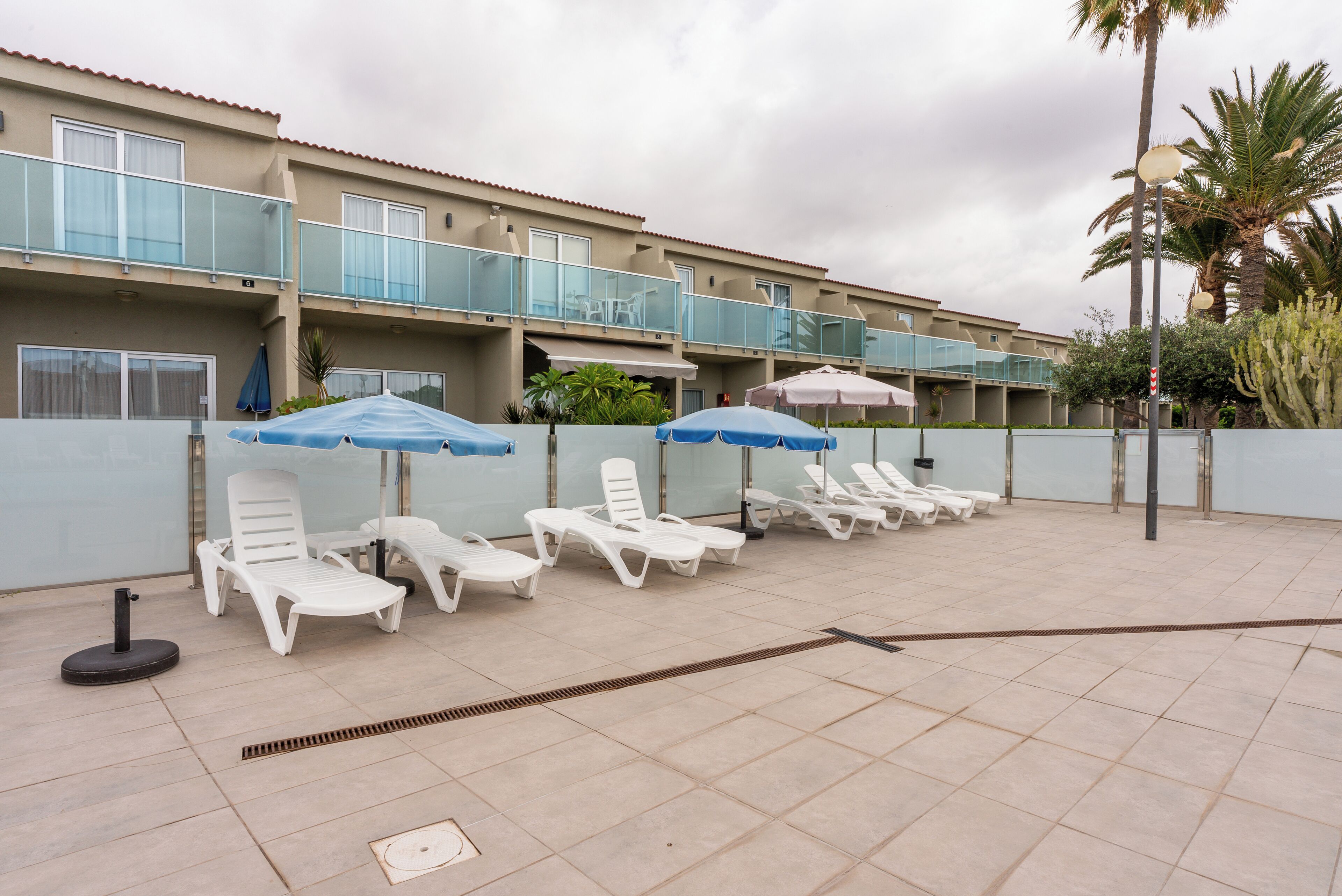 A hotel with multiple balconies, outdoor seating with umbrellas, and a tiled patio area.