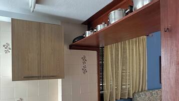 Een compacte keuken met houten kastjes, een aanrecht en een eethoek met stoelen.