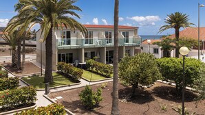 Un hotel con balcón, palmeras y vista al mar.