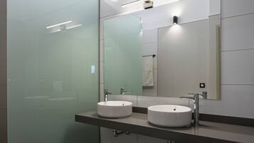 A modern bathroom with two round sinks, a large mirror, and a glass shower enclosure.