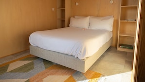 Een net opgemaakt bed in een kamer met houten wanden en inbouwplanken.
