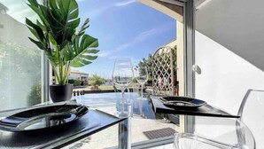 Ein Balkon mit einem Glastisch, zwei Weingläsern und einem Blumentopf.