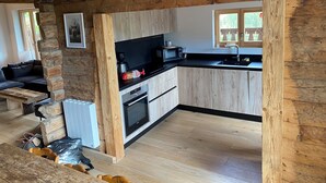 Una cocina rústica con vigas de madera, encimera negra y horno empotrado.