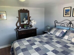 Un dormitorio con cama, cómoda, espejo y mesita de noche.