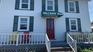 A two-story building with a green awning labeled 'HILLSIDE B&B' and a red door. - Historic Hillside Vacation Home (Twillingate)