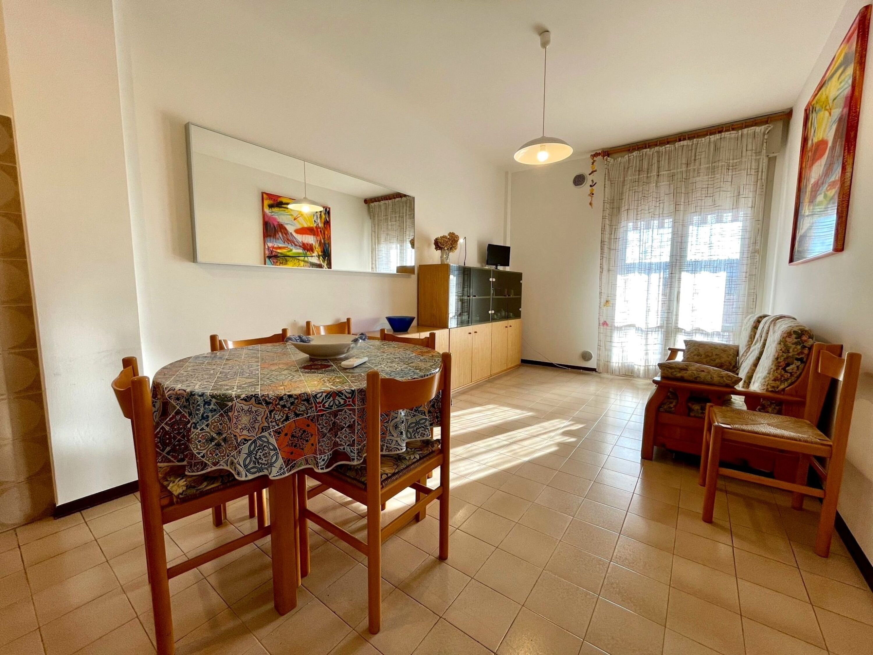 A dining area with a round table, chairs, a cabinet, and a television.