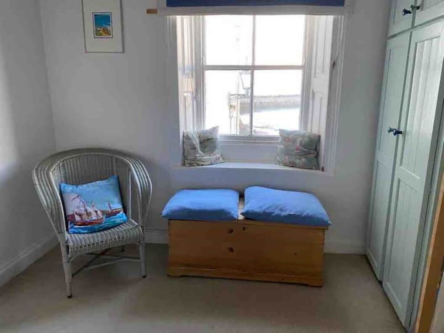 Une pièce avec un siège de fenêtre, une chaise en osier avec un coussin et un banc en bois agrémenté de coussins.