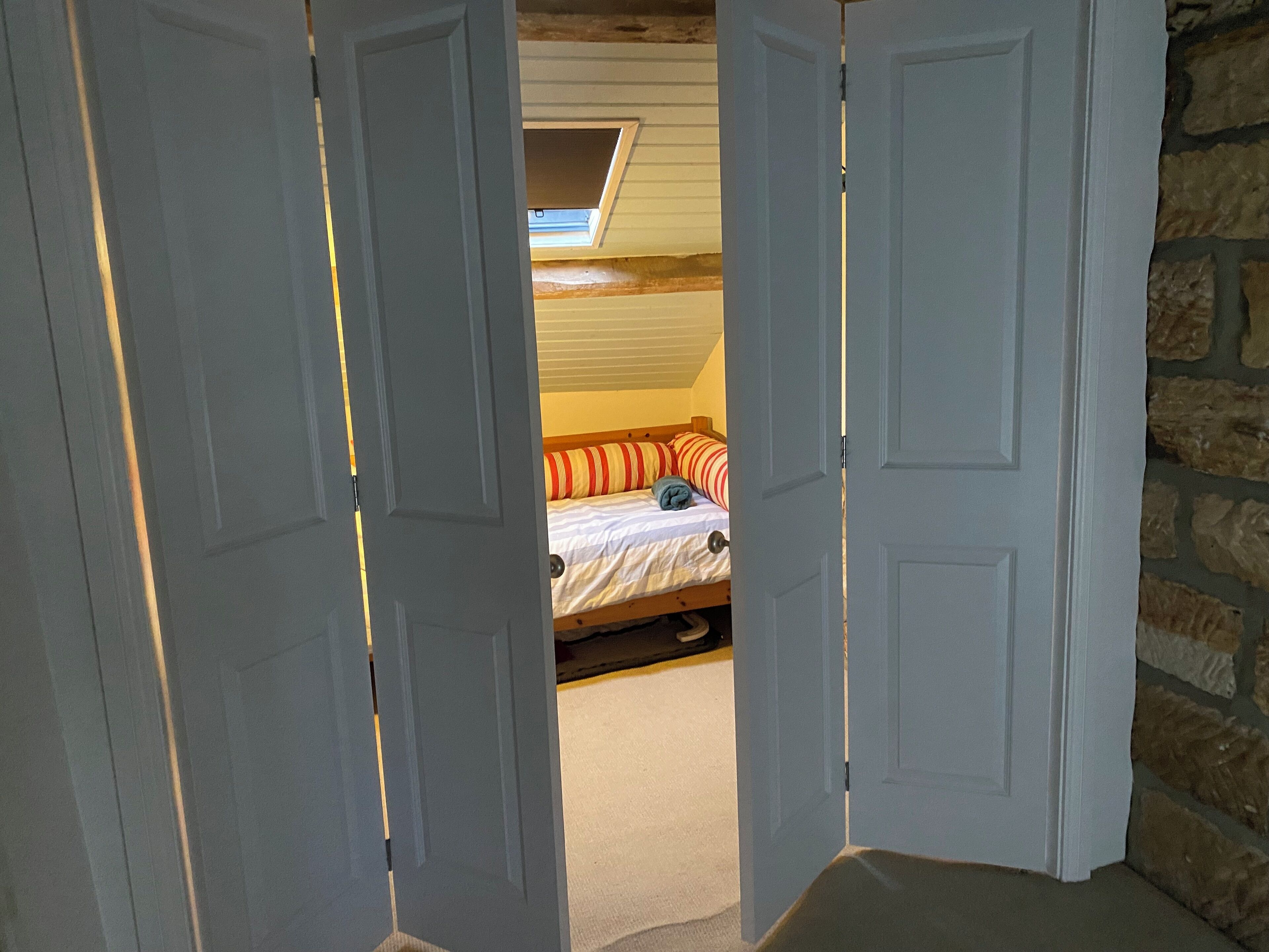 Ein Schlafzimmer mit Bett, Fenster und einer Steinwand.
