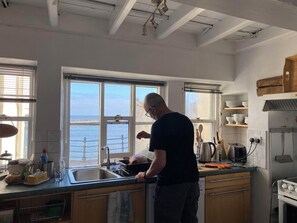Een keuken met uitzicht op zee, een kookplaat en een spoelbak.