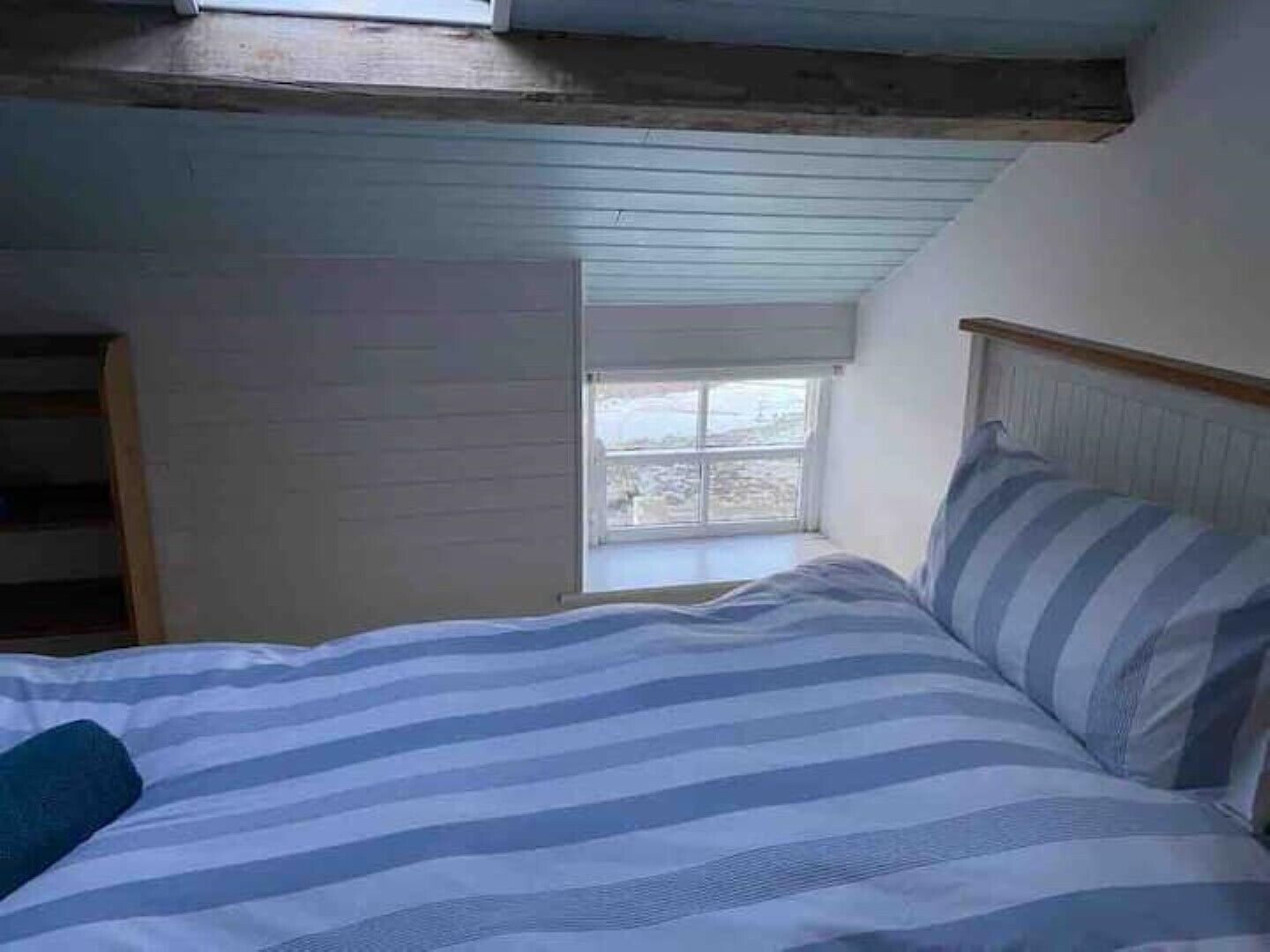 Une chambre à coucher avec un lit, une fenêtre et un plafond en pente.