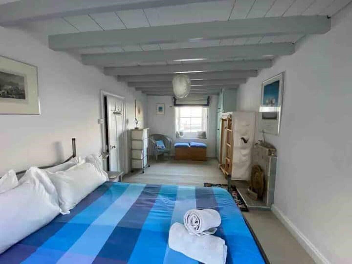 Een slaapkamer met een groot bed, een nachtkastje, een kledingkast en een raam.