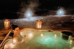 Une personne dans un bain à remous, avec deux bougies, entourée de brume.