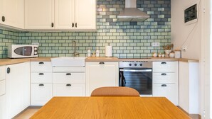 A kitchen with white cabinets, a microwave, an oven, and a tiled backsplash. - Beach Front Luxury Designer Two Bedroom Apartment (CT)