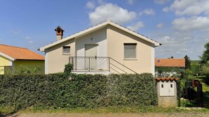 A single-story house with a tiled roof, a small balcony with a metal railing, and a white door. - Holiday apartment with parking space and with air conditioning (Medulin)