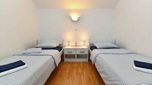 A small, well-lit bedroom with two single beds, a nightstand, and a wall-mounted light fixture. - Holiday apartment with parking space and with air conditioning (Medulin)