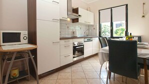 Eine moderne Küche mit weißen Schränken, einem eingebauten Backofen und einem Essbereich mit Tisch und Stühlen.