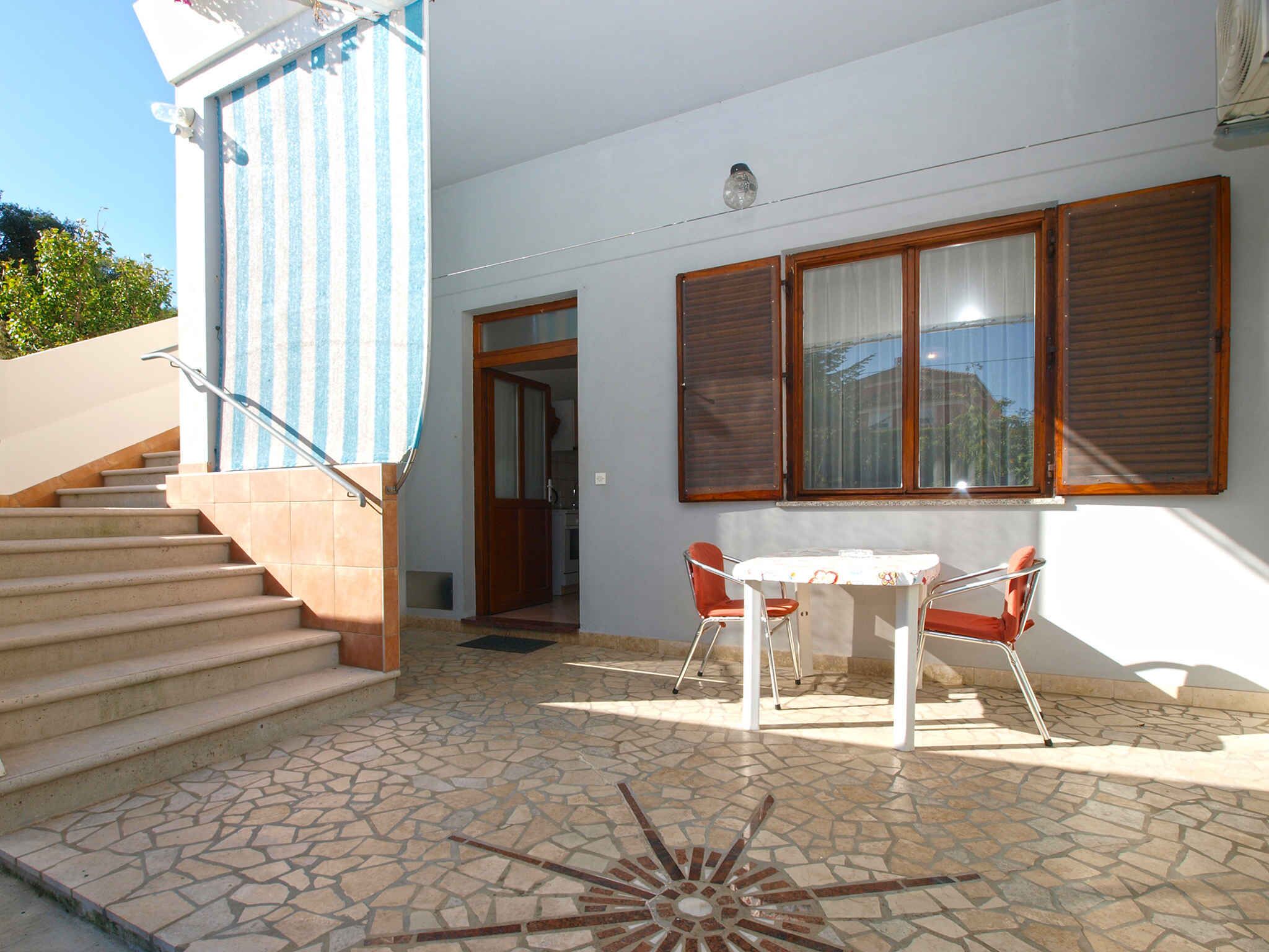 Un bâtiment à deux étages doté d’un patio carrelé, d’un escalier et d’un coin repas avec une table et des chaises.