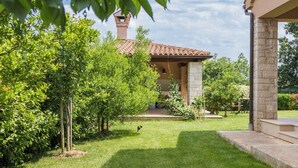 A well-maintained garden with a stone pathway leading to a building with a tiled roof. - Holiday apartment with pool (Ližnjan)