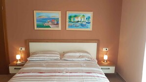 A bedroom with a bed, two bedside lamps, and two paintings on the wall. - Holiday apartment with pool (Ližnjan)
