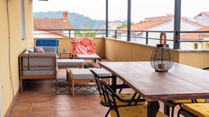 A balcony with a wooden table, yellow chairs, a sofa, and a red patterned tablecloth. - Holiday apartment with air conditioning (Pula)