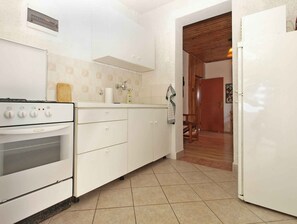 A kitchen with white cabinets, a stove, and a refrigerator. - Holiday apartment with air conditioning (Premantura)