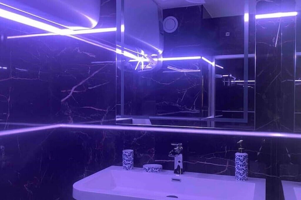 A modern bathroom with a marble wall, a white sink, and a mirror.
