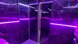 Une pièce dotée d’une cloison en verre, d’un éclairage violet et d’un sol qui ressemble à du marbre.