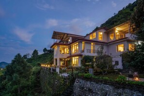 A two-story house with multiple balconies, surrounded by lush greenery and a stone wall. - Shambhal House (Nainital)