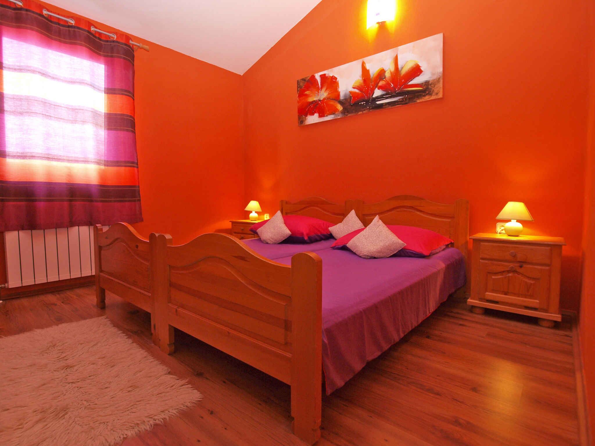 A bedroom with a wooden bed, purple bedding, and two bedside lamps.
