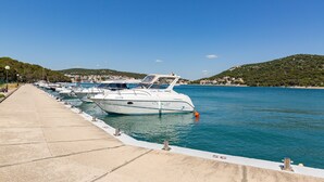 Un puerto deportivo con varias embarcaciones amarradas a lo largo de un muelle de hormigón.